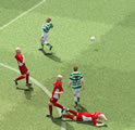 A player from one football team kicks the ball off the pitch as a player from the other team lies on the ground.
